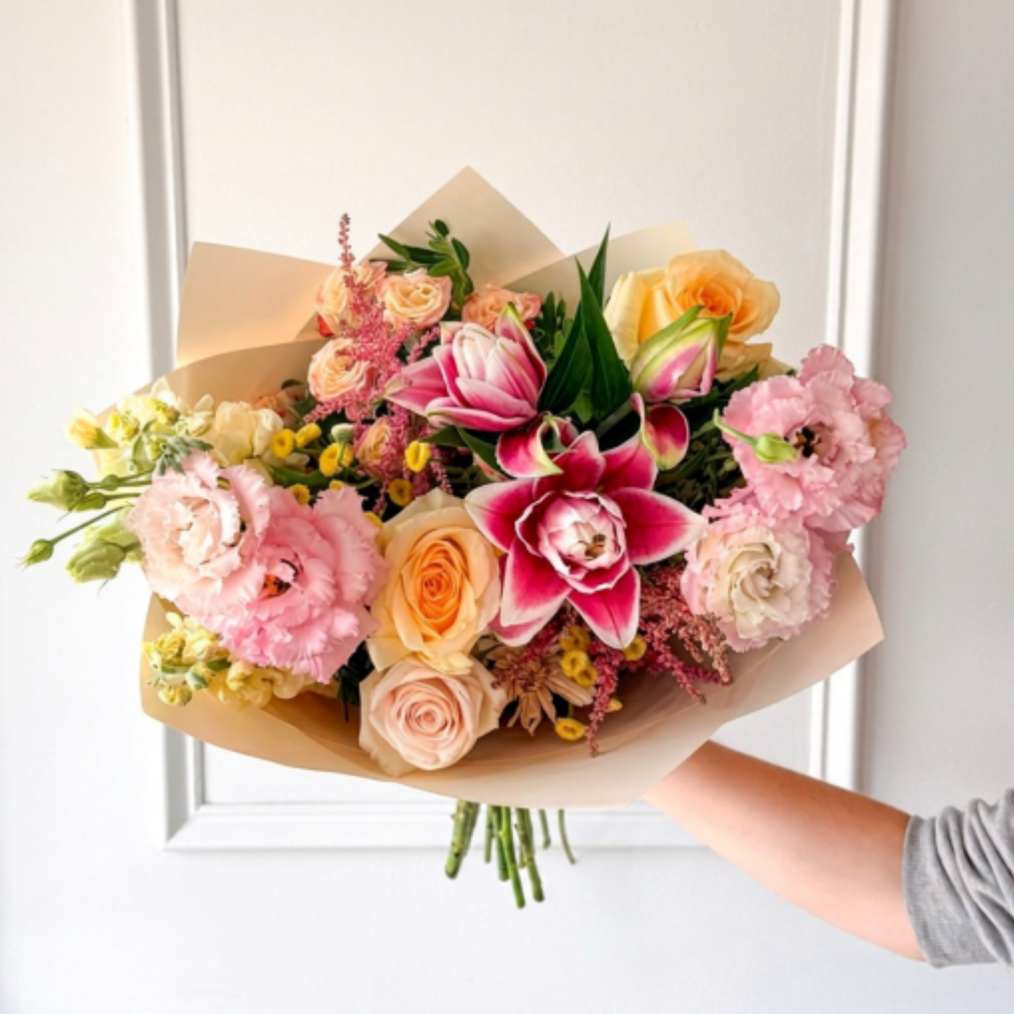 A summer bouquet of lilies, roses, and lisianthus wrapped in premium paper for delivery or pickup in Edina, Minneapolis and Minnetonka. 