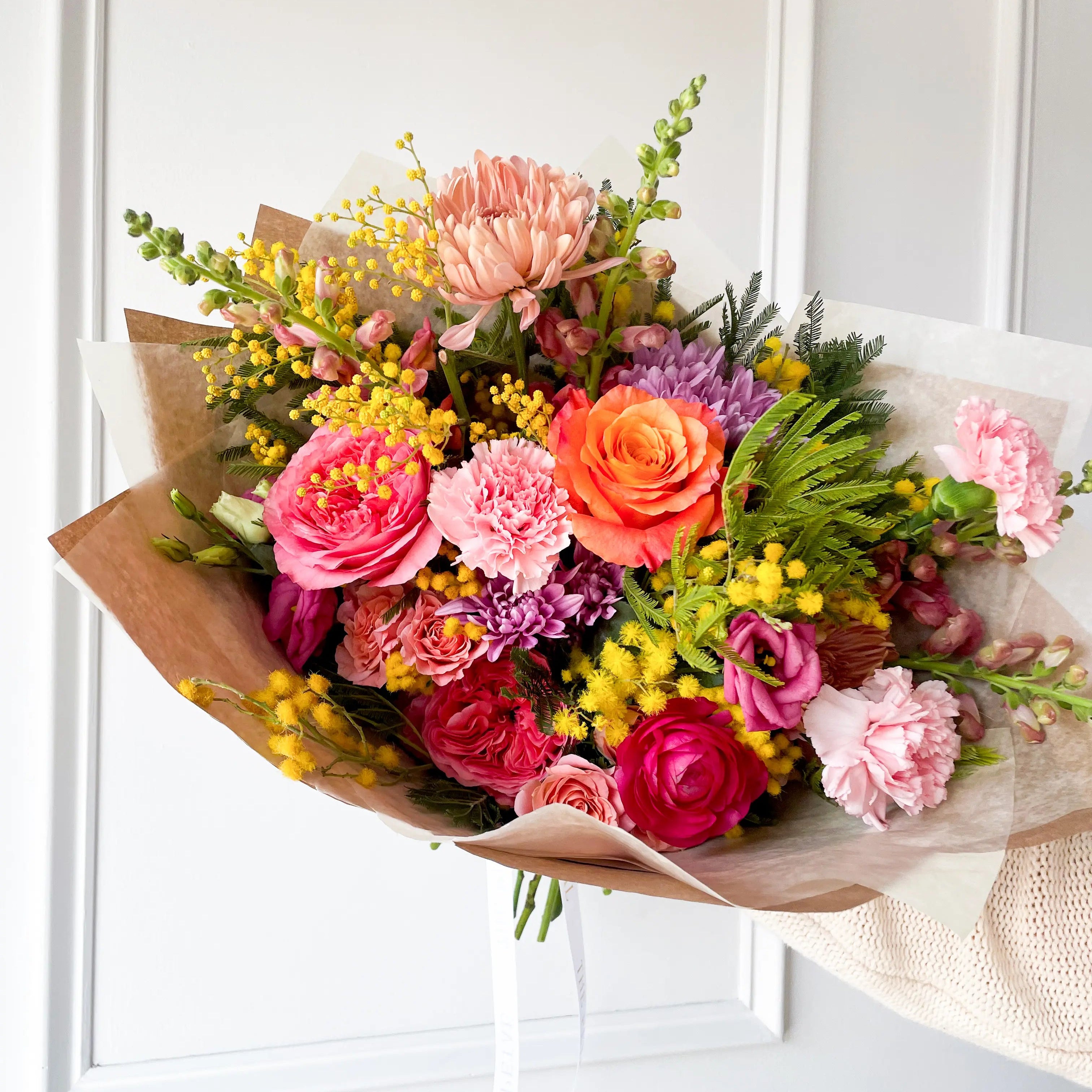 Colorful blooms in a hand-tied bouquet wrapped in Kraft paper.