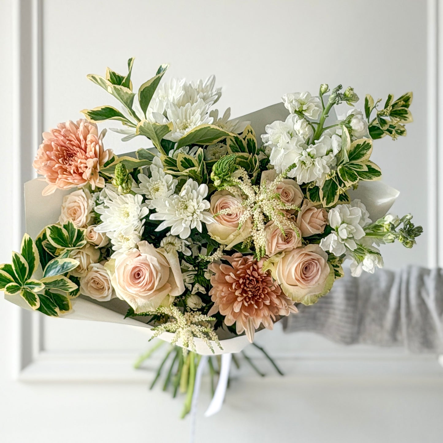 Bouquet of white, peach, and blush pink roses, cremons, and accents designed in a hand-tied bouquet for pickup or delivery in Minneapolis, Edina, Eden Prairie and Linden Hills.