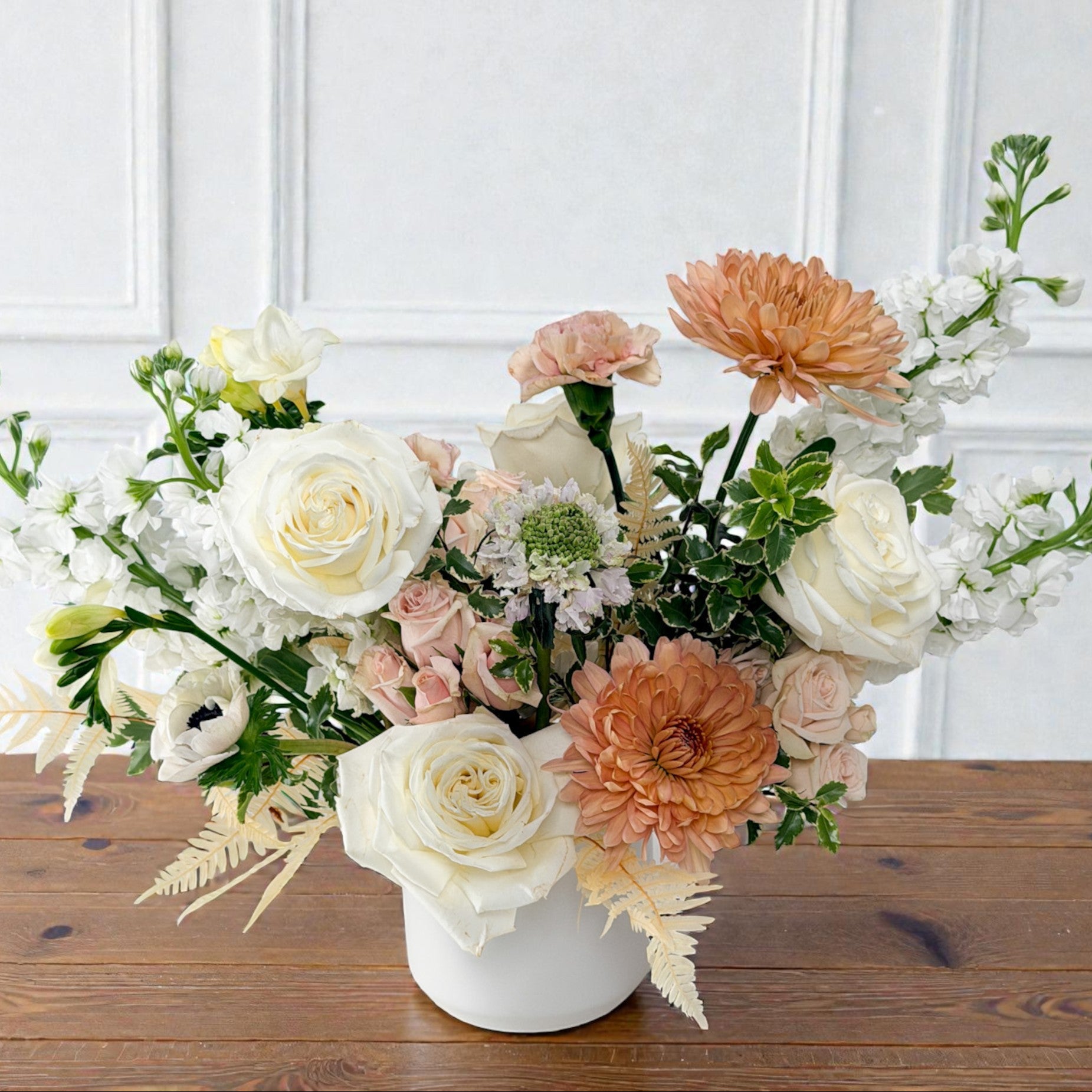 Luxury soft neutral floral arrangement in a white ceramic vase featuring white roses, peach mums, and airy greenery for elegant home decor or gift delivery in Edina.
