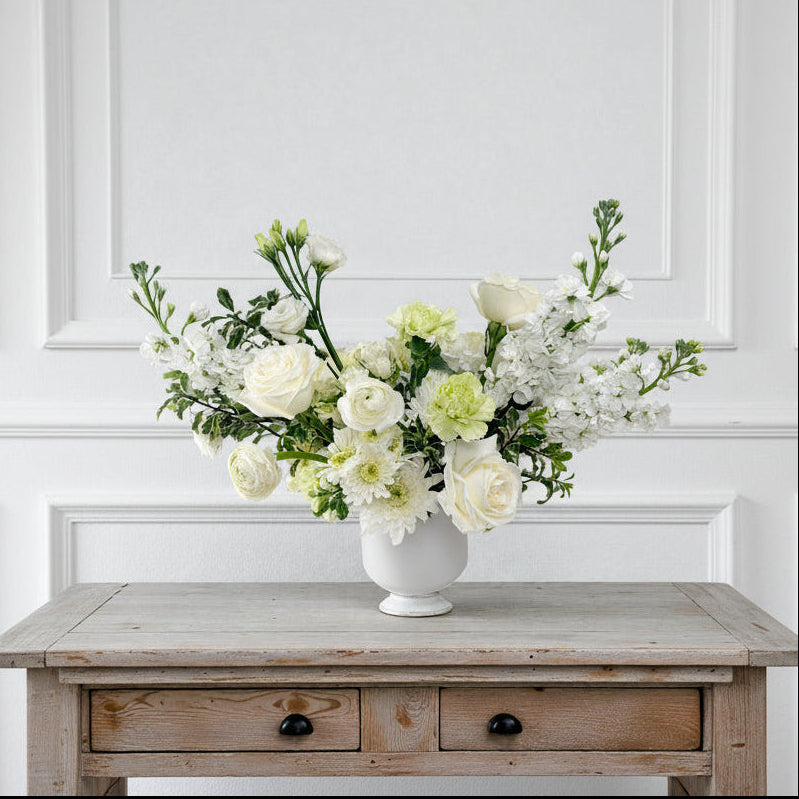 Signature $150 white and green floral arrangement in a white ceramic vase featuring premium white roses and lush seasonal greenery, available for pick up  in Edina, Minnesota or local flower delivery to the South & West Metros.