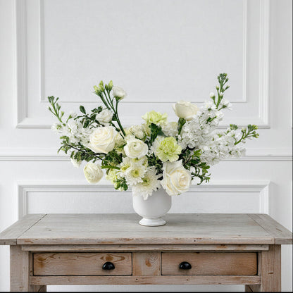 Signature $150 white and green floral arrangement in a white ceramic vase featuring premium white roses and lush seasonal greenery, available for pick up  in Edina, Minnesota or local flower delivery to the South & West Metros.