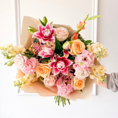 A pink and yellow bouquet of summer flowers hand-tied and wrapped in premium paper from The Petal for delivery in Minneapolis, Richfield, Golden Valley, and Bloomington.