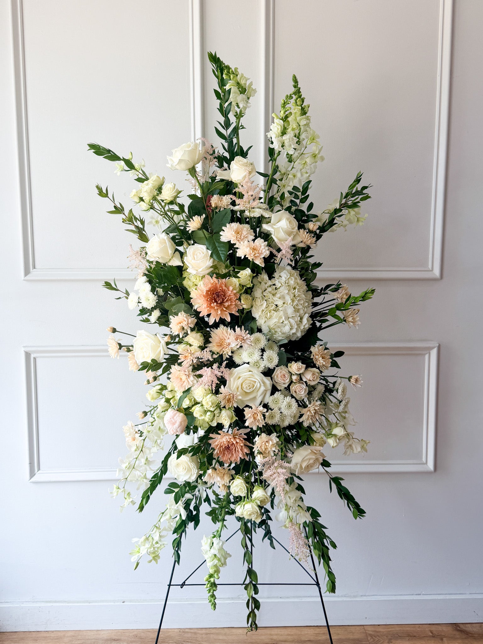 A gorgeous standing spray filled with soft blush, ivory and peach flowers perfect for a funeral or memorial service elegantly displayed on an easel. Order for delivery in Minneapolis, Edina, Minnetonka, St. Louis Park and Golden Valley.