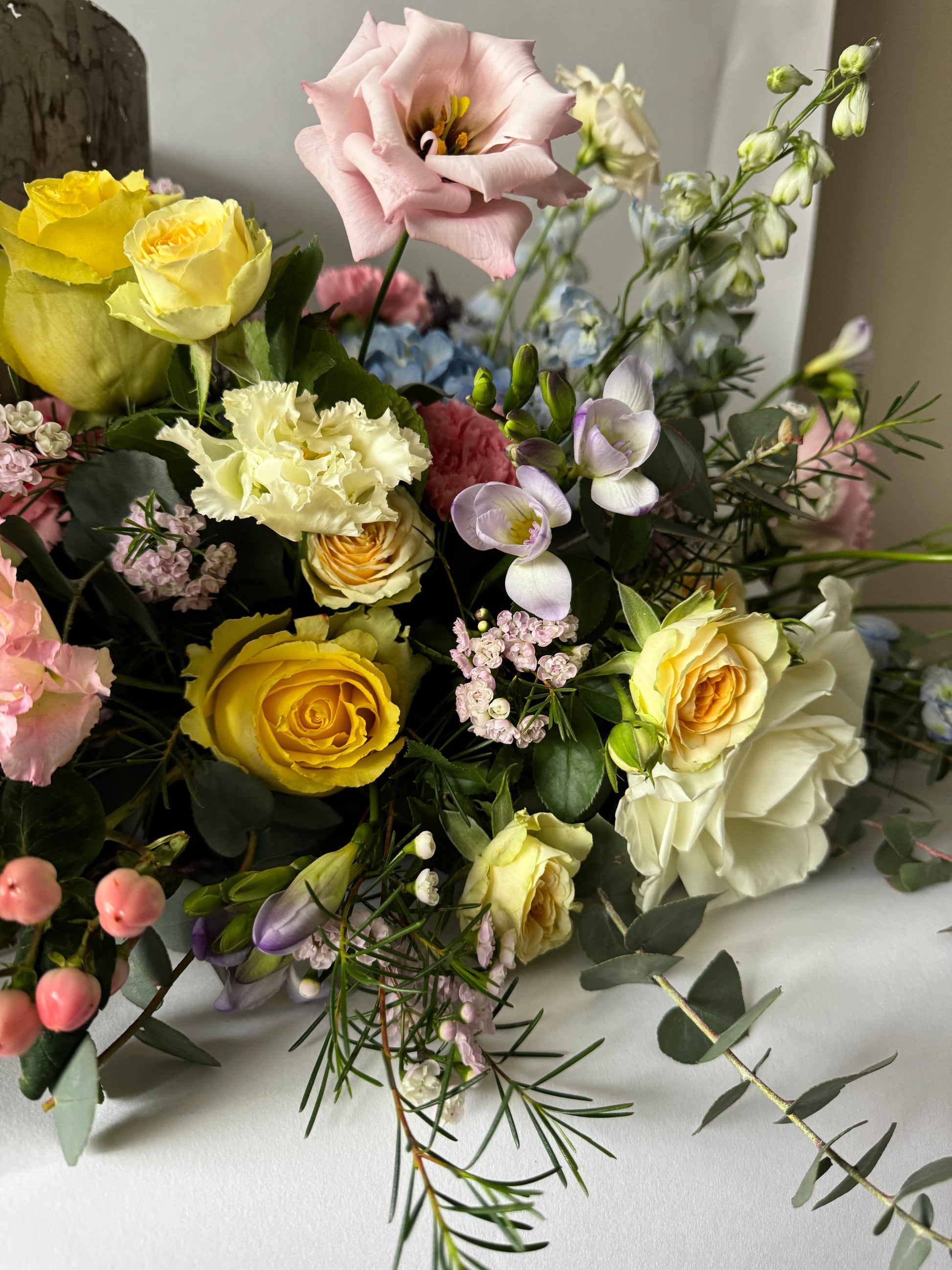 Memorial flowers arranged with a variety of flowers including purples, pinks, whites, and greens, displayed in a ceramic vase.