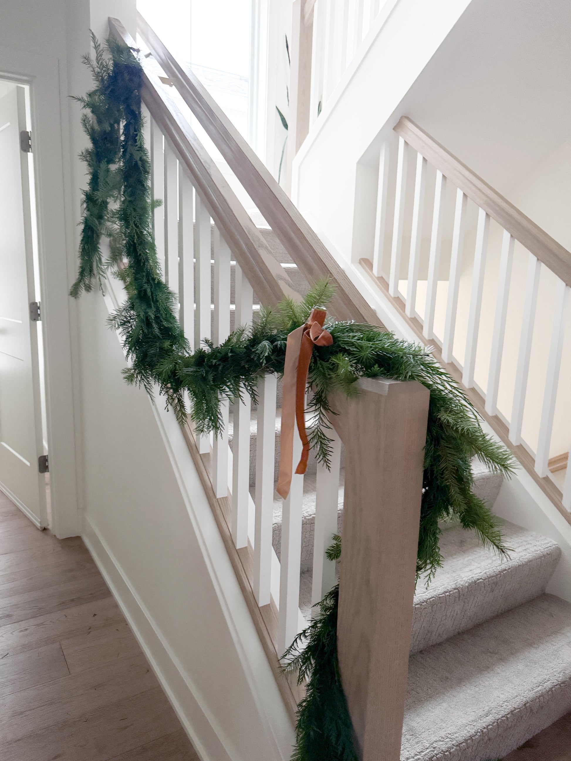 Custom Christmas garland with lush evergreen branches and festive bows, perfect for decorating mantels, staircases, or holiday spaces, available for Edina pick-up or Minneapolis delivery