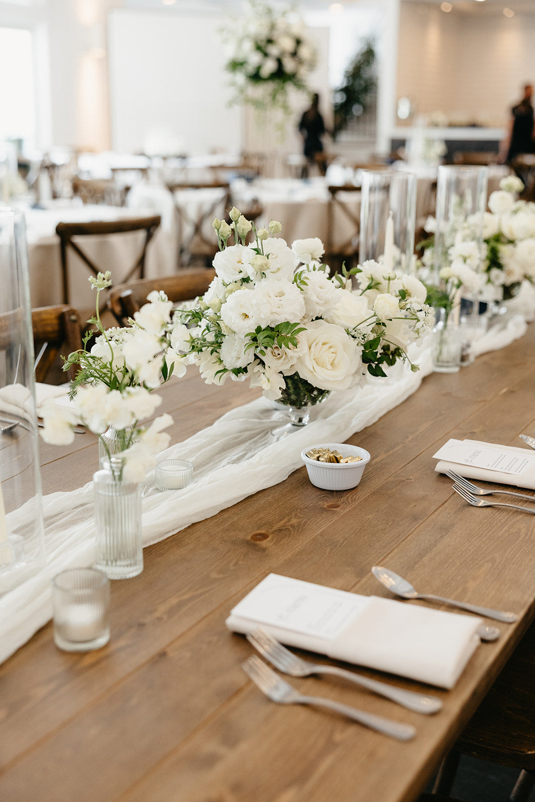 Elegant wedding reception head table setup with lush white floral centerpieces, bud vases and candles for a high-end wedding in minneapolis minnesota by The Petal