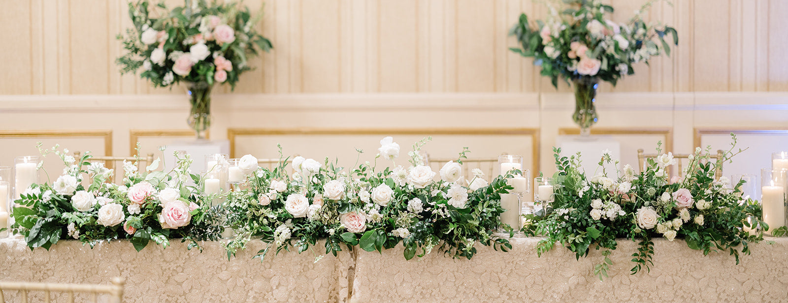 Lush, sprawling wedding head table floral arrangement at The Saint Paul Hotel featuring white roses, hydrangeas, and organic greenery by The Petal: a local wedding florist.