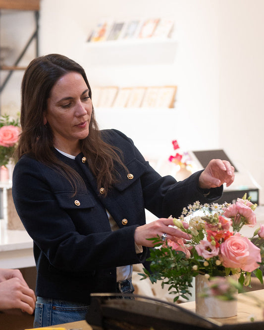 Woman arranging flowers in a floral shop for a floral centerpiece workshop