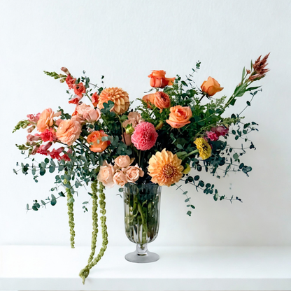 Order now! Our Deluxe sized arrangement designed in a glass vase, including soft orange, peach, coral, and mauve tone blooms to create show-stopping floral designs. Same-day pickup or delivery available!
