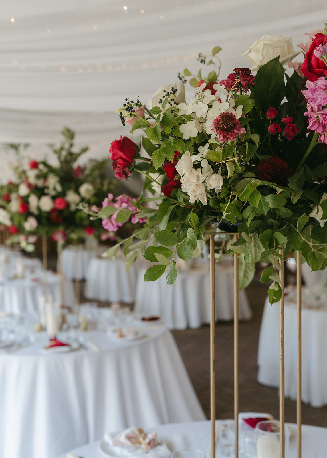 lush elevated tall floral centerpieces on gold stand for indian wedding reception in tent in Minnesota by The Petal