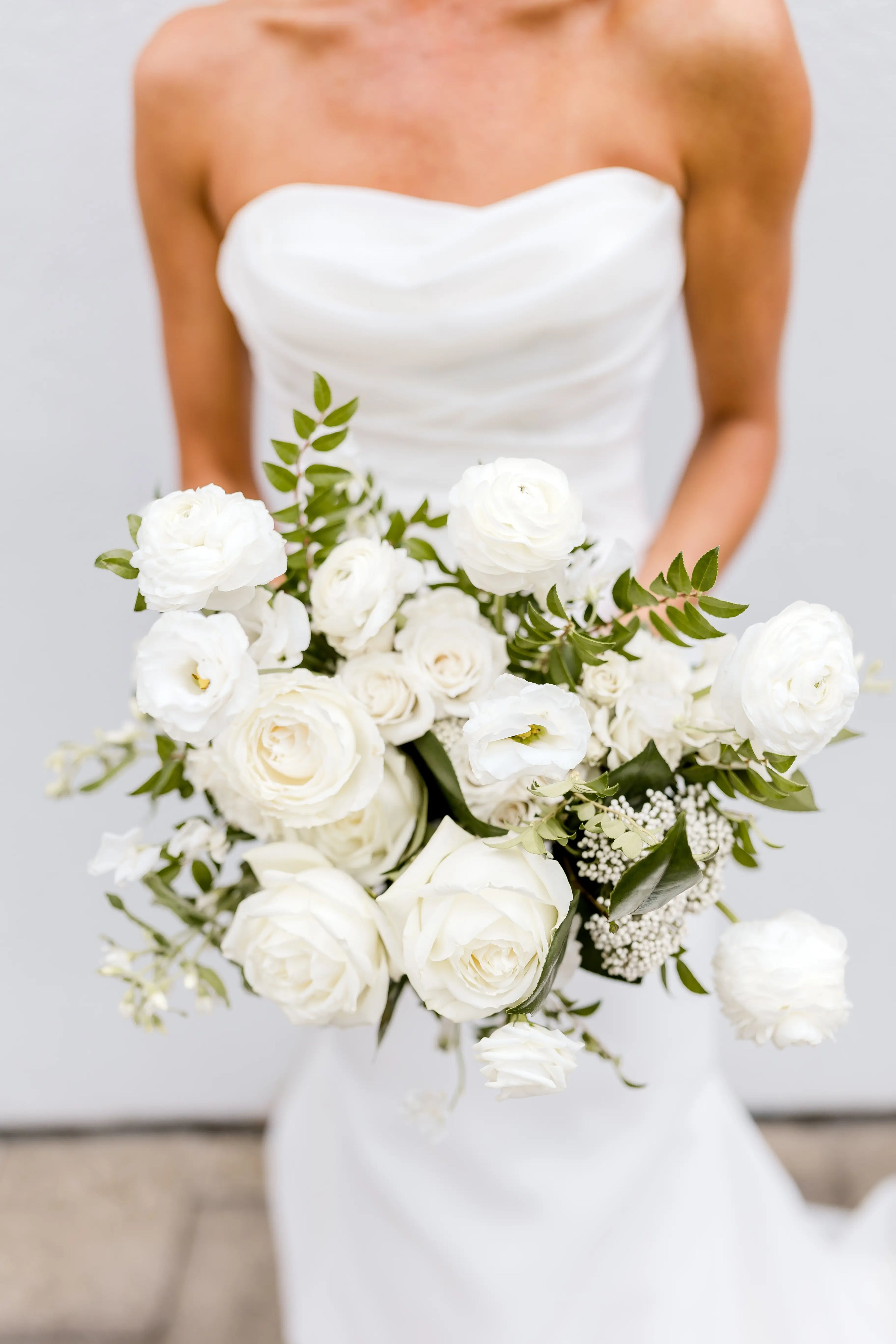 A bridal bouquet with white roses and  sprawling greenery.