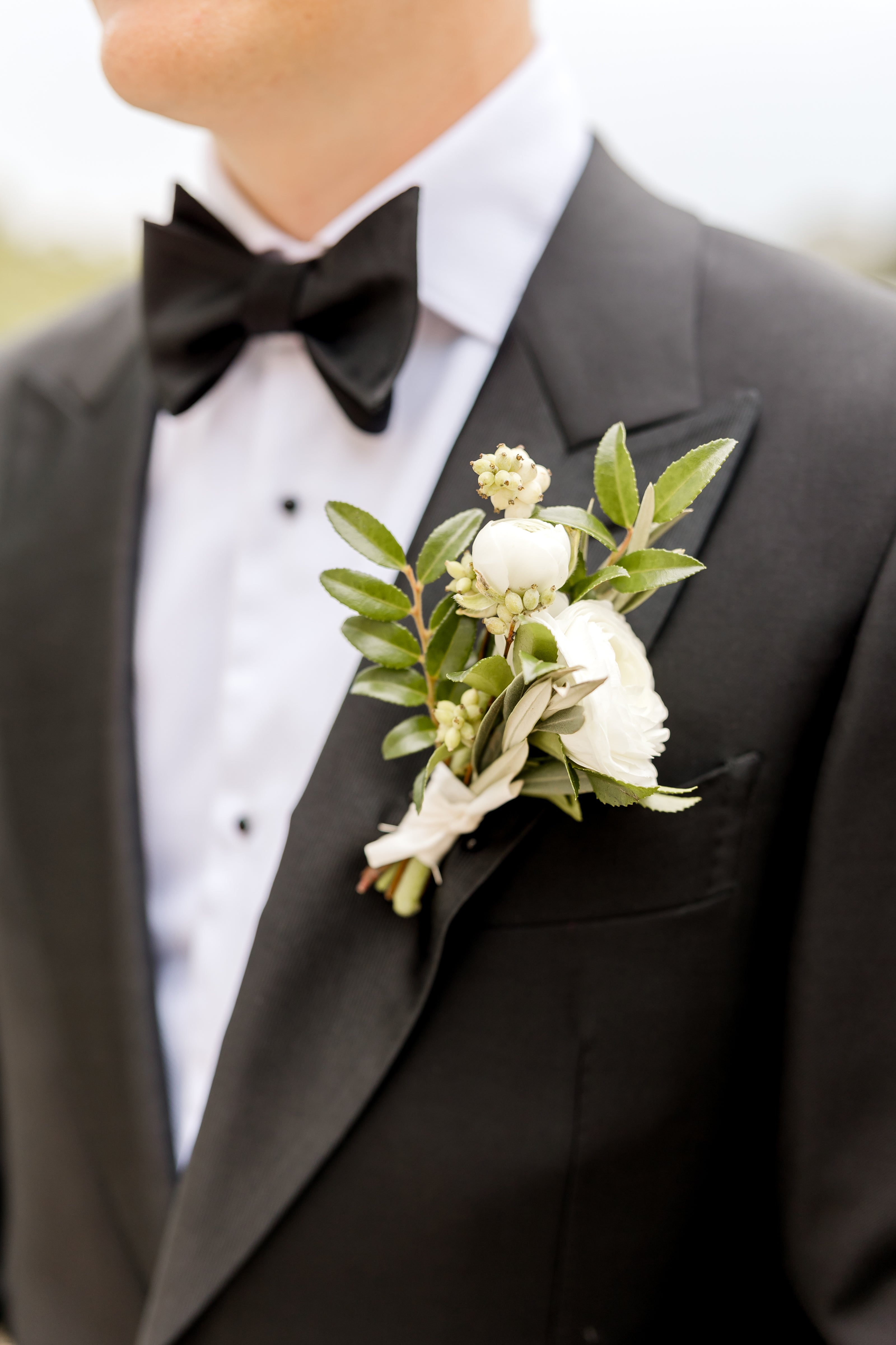 Man wearing a tuxedo wearing a classic white and green boutonniere for a wedding, homecoming, prom or other special event.  Order for pickup in Edina.