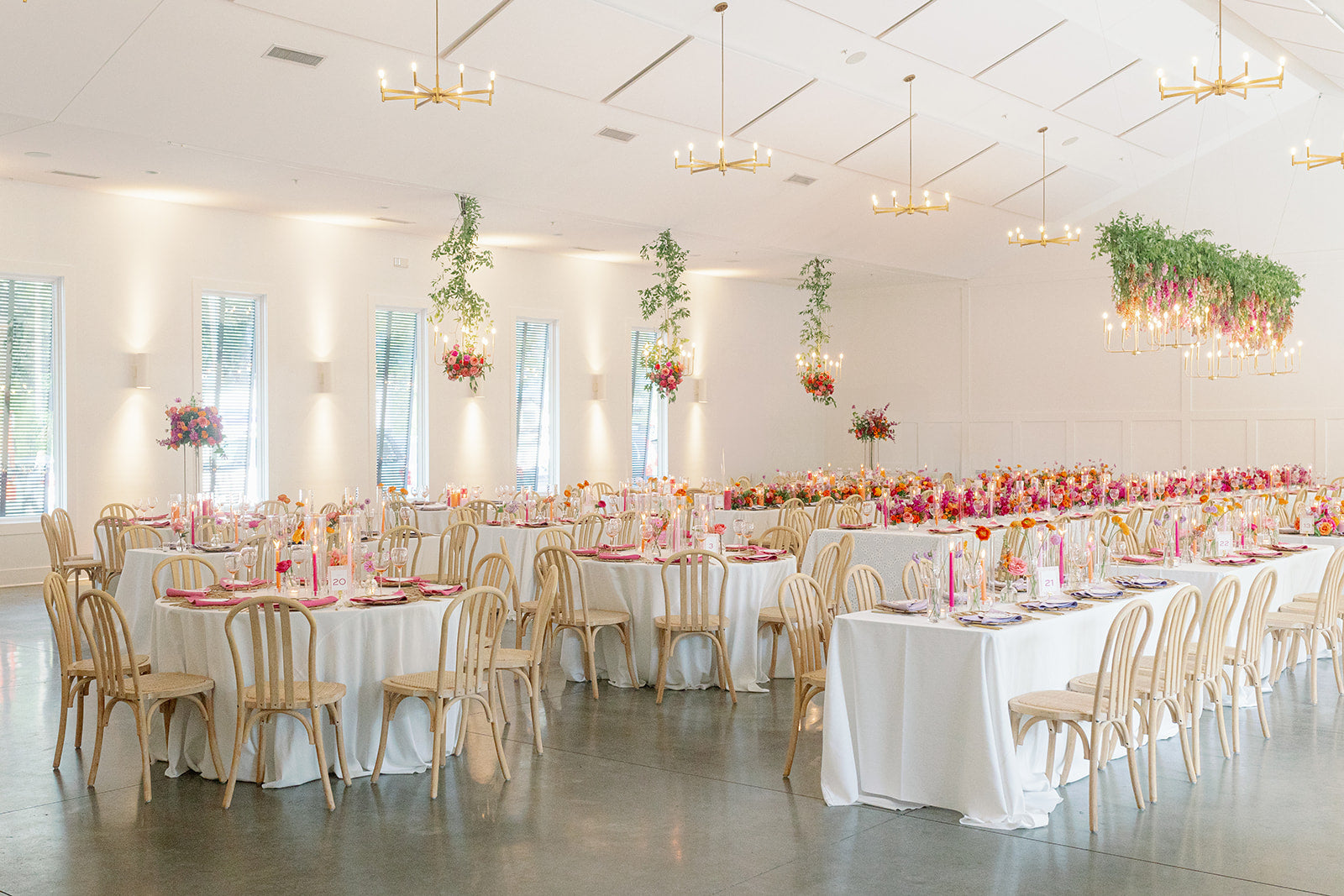 High-end, luxury wedding reception with hanging installation, chandeliers and colorful centerpieces at Hutton house.