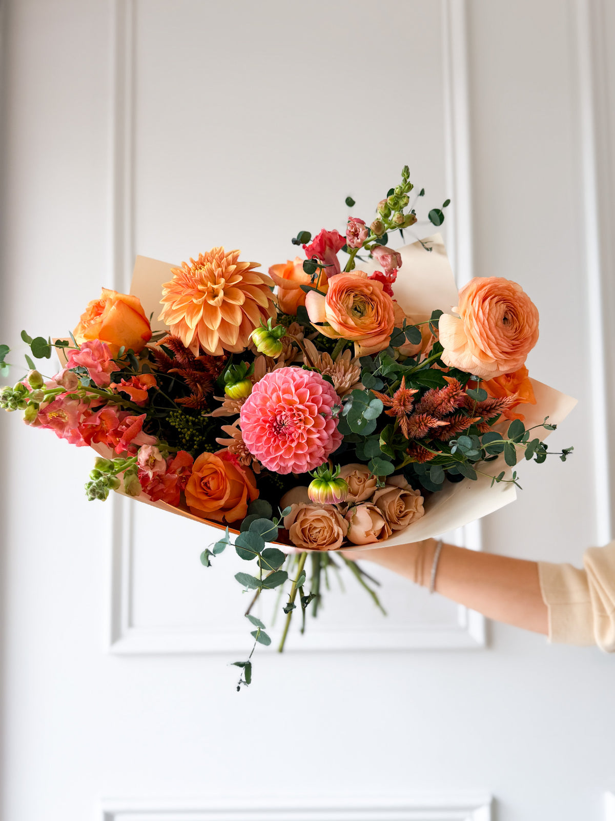Enjoy October with our premium bouquet showcasing a warm palette of bright coral, dusty mauve, soft peach, and gentle orange accents balanced with leafy green foliage. Beautifully wrapped in paper for same-day delivery across Minneapolis, Edina, Wayzata, and Minnetonka.