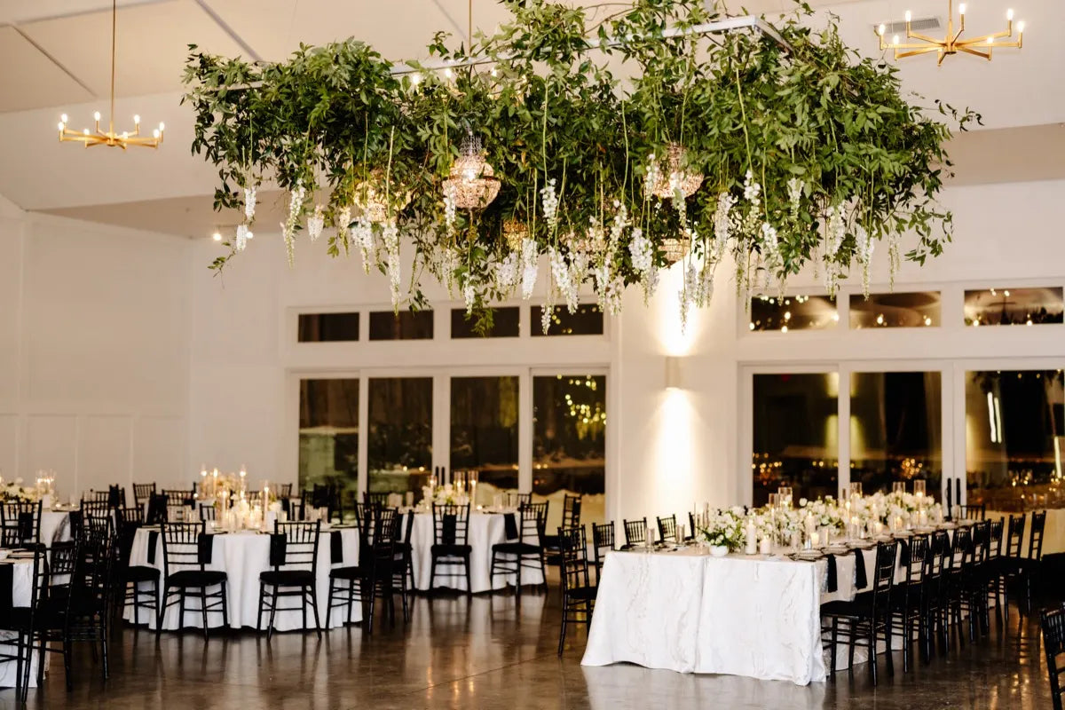 Lush greenery and dangling delphinium and chandelier hanging installation over the dance floor of a winter wedding at the hutton house. Planned by Whitney James Events. Floral Design by The Petal.