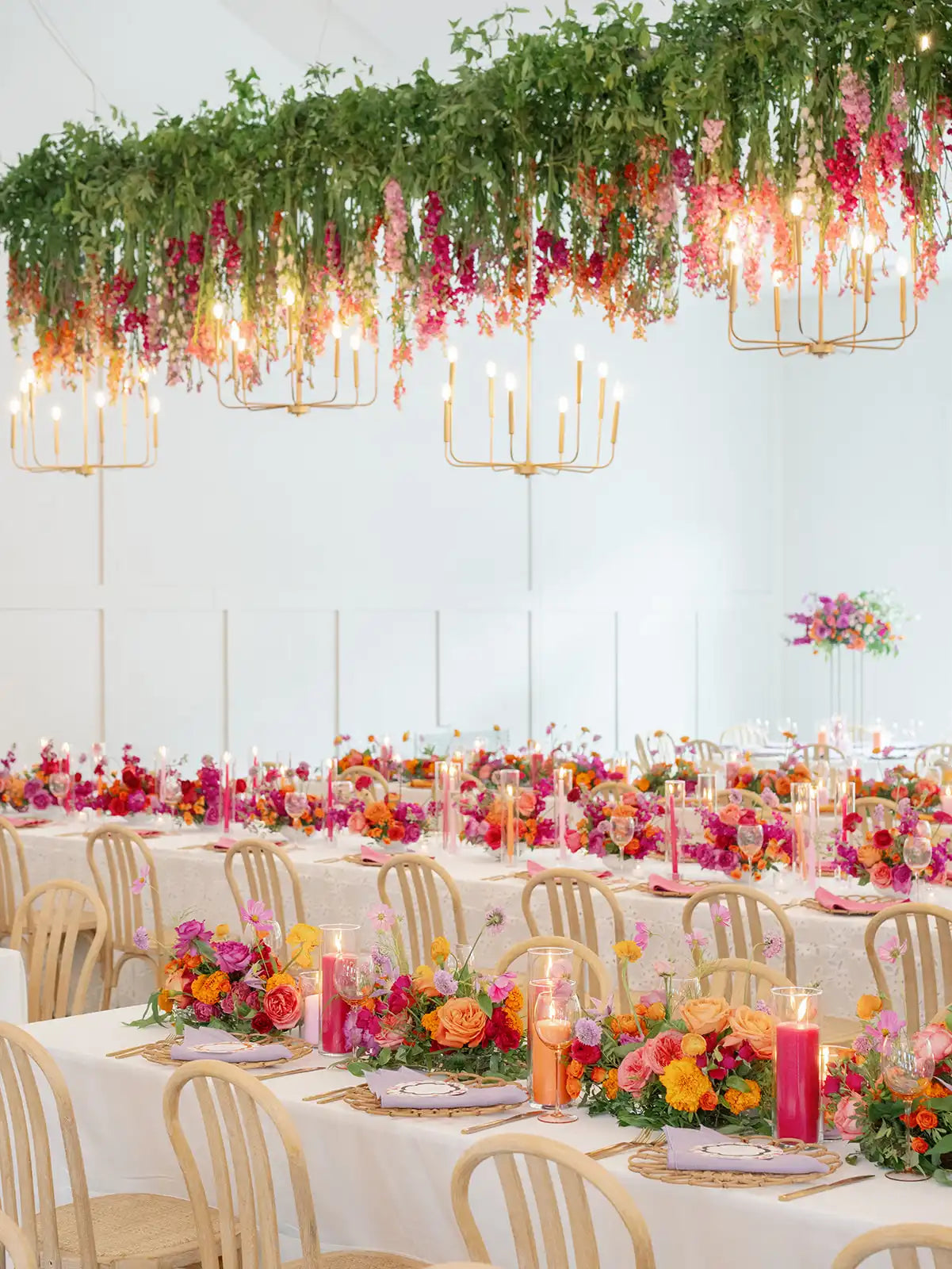 Lush hanging installation of colorful flowers and greenery over the head table filled with colorful luxury florals and candles for the perfect summer wedding. Florals by The Petal, Photo by Amanda Nippoldt, Planning by Pink Peony. Venue The Hutton House.