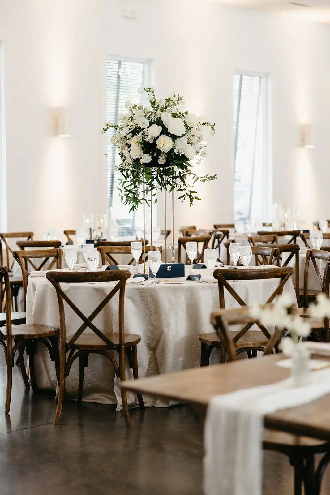 Tall garden-style wedding centerpiece featuring white roses and lush greenery on a gold stand, set for a reception at The Hutton House in Minneapolis by The Petal Floral Design.