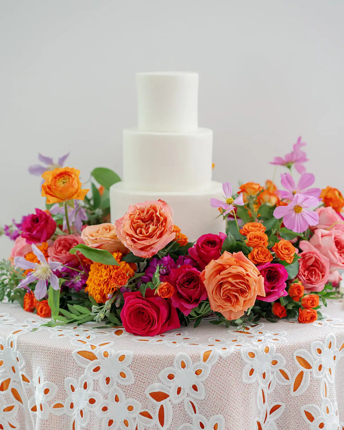 White wedding cake with colorful, seasonal blooms.