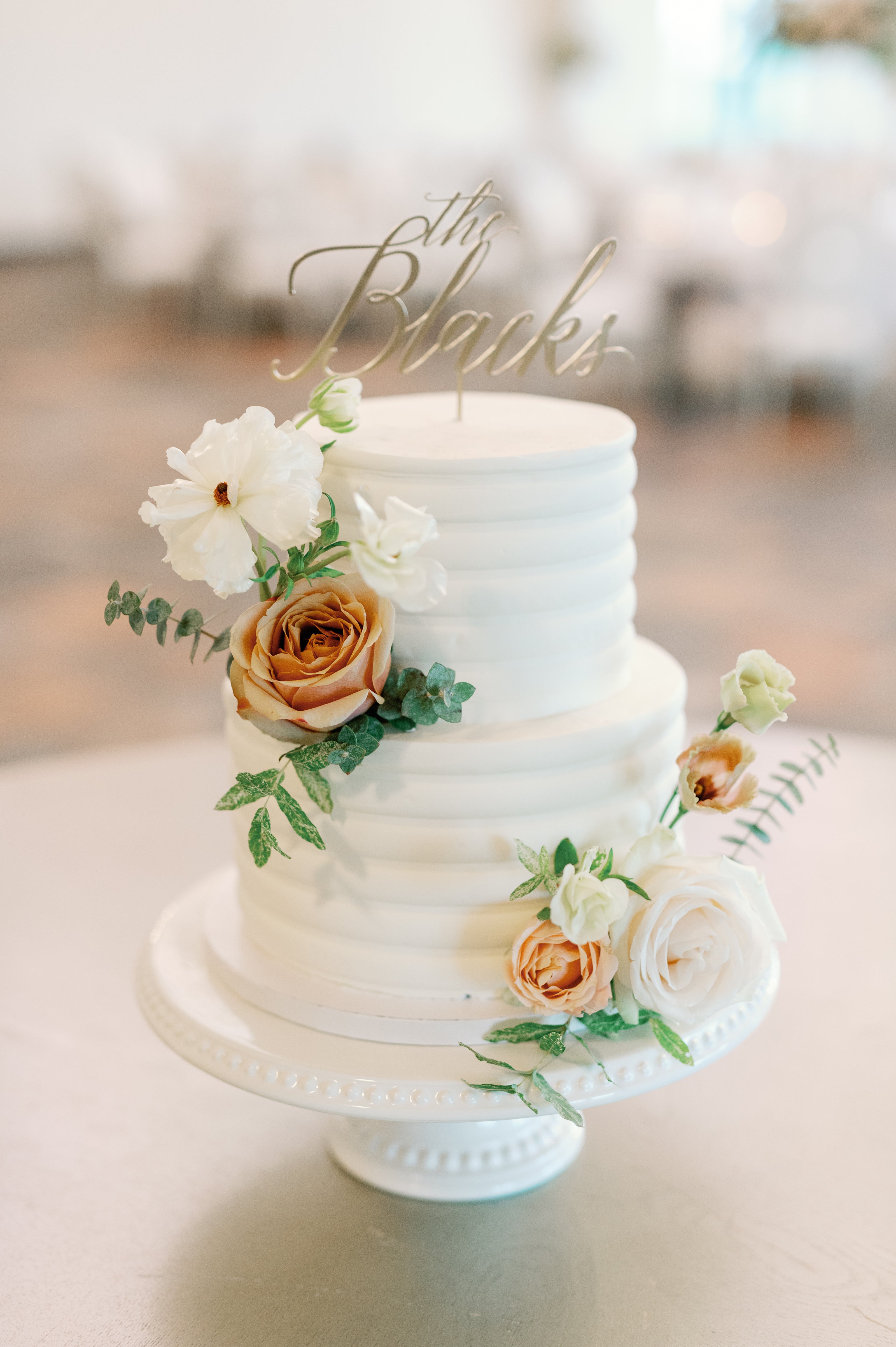 Two-tiered wedding cake with floral decorations on white buttercream designed by The Petal, Minneapolis Wedding Florist