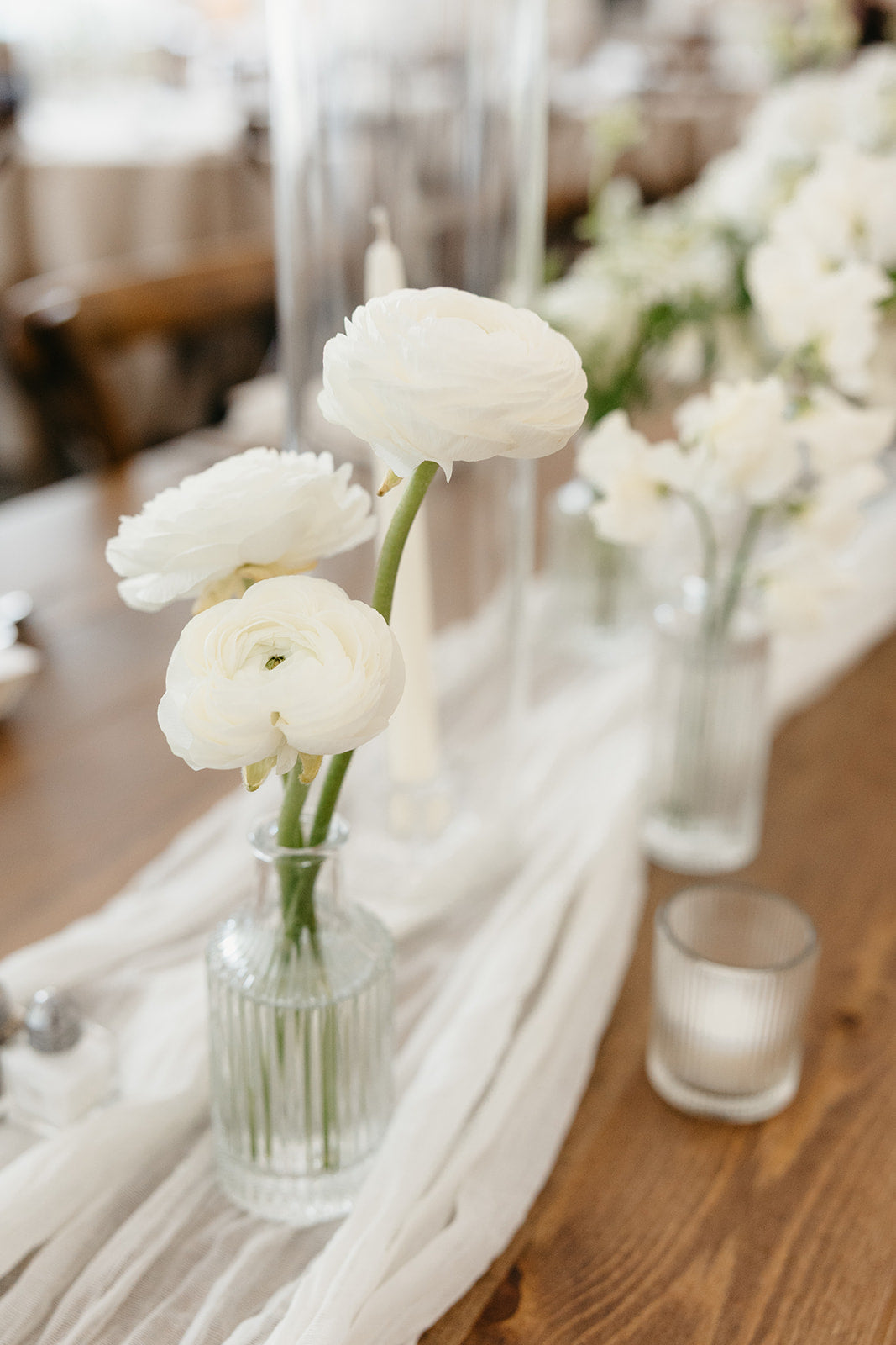 White flowers in a vase on a wooden table with white silk runner for luxury wedding in minneapolis